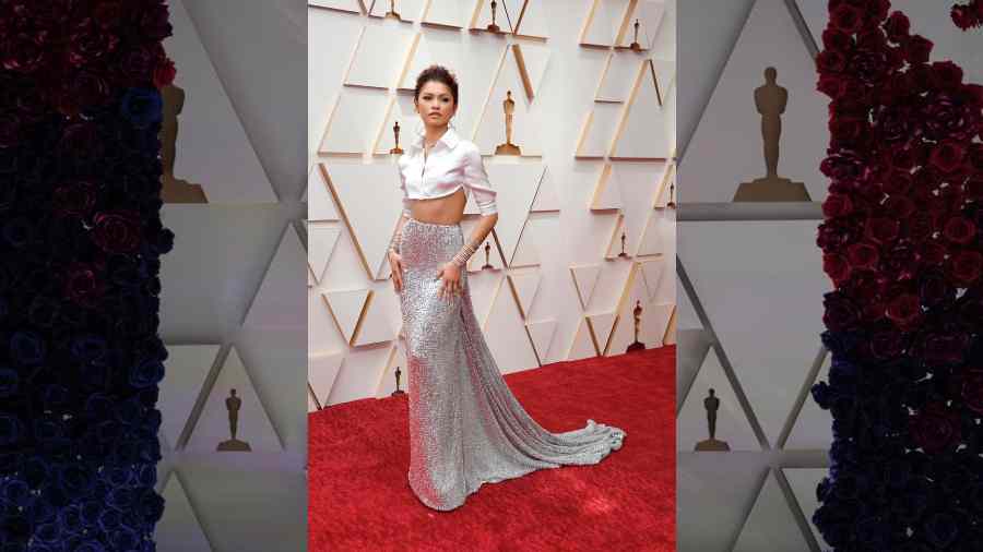 Would anyone dare to wear a sequinned long skirt with a cropped white shirt on the Oscar red carpet? Well, Zendaya just did! The actress accompanied her Valentino Haute Couture ensemble with a sleek neckpiece and statement-y spiral bracelets on both her wrists. A messy updo with some wisps and nude make-up completed her look.