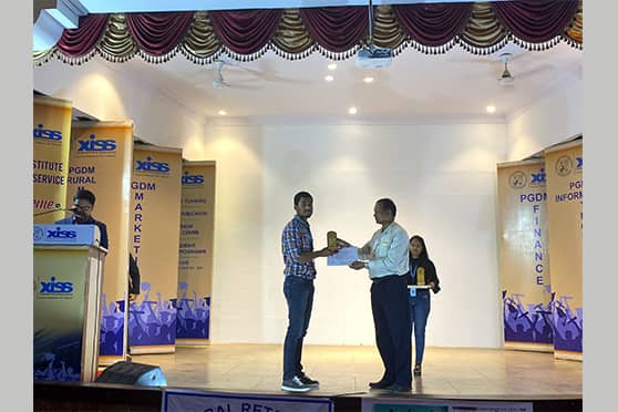 A student receives a certificate and prize from XISS director Joseph Marianus Kujur.