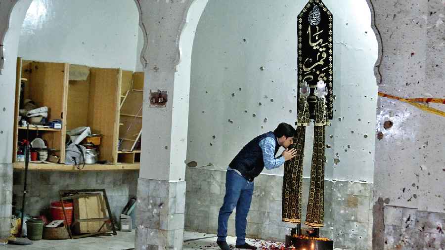 A man kisses a religious wall-hanging in the Kusha Kisaldar mosque, the site of the March 4 suicide bombing, in Peshawar. The bomber, an Afghan identified by the Islamic State as Julaybib al-Kabuli, was from Kabul. 