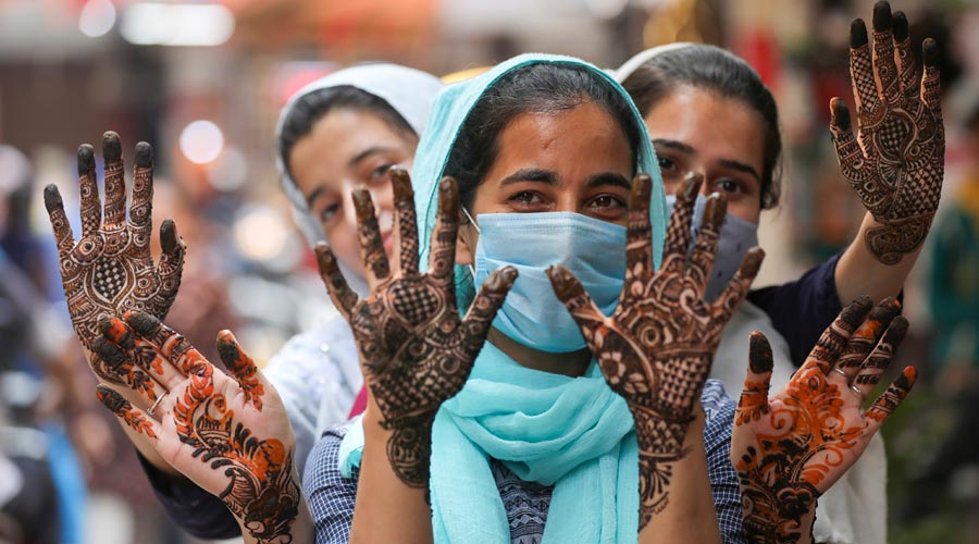 Muslim women show freshly applied henna on their hands, ahead of the Eid-ul-Fitr festival, in Jammu