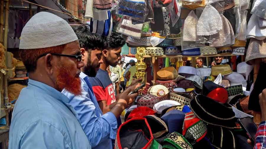 Muslims examine the Taqiyah, a short, rounded cap worn for religious purposes, while shopping ahead of the upcoming festival of Eid-ul-Fitr, in front of Nakhoda Masjid, in Kolkata