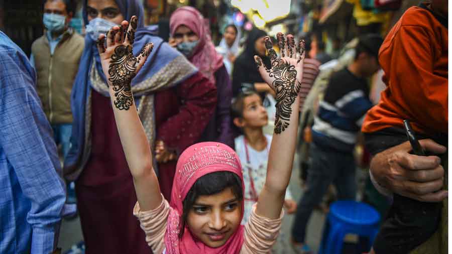 A girl walks with her hands raised up after getting them decorated with henna on the eve of Eid-ul-Fitr, which marks the end of the holy month of Ramadan, in Srinagar