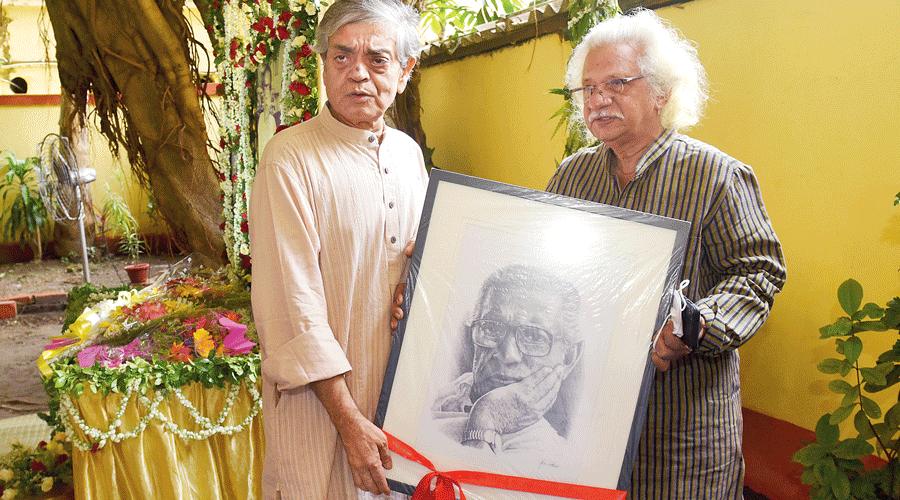 Adoor Gopalakrishnan (right) hands over a portrait of Satyajit Ray to his son Sandip Ray on the 101st birth anniversary of the cinema legend at his Bishop Lefroy Road home on Monday.