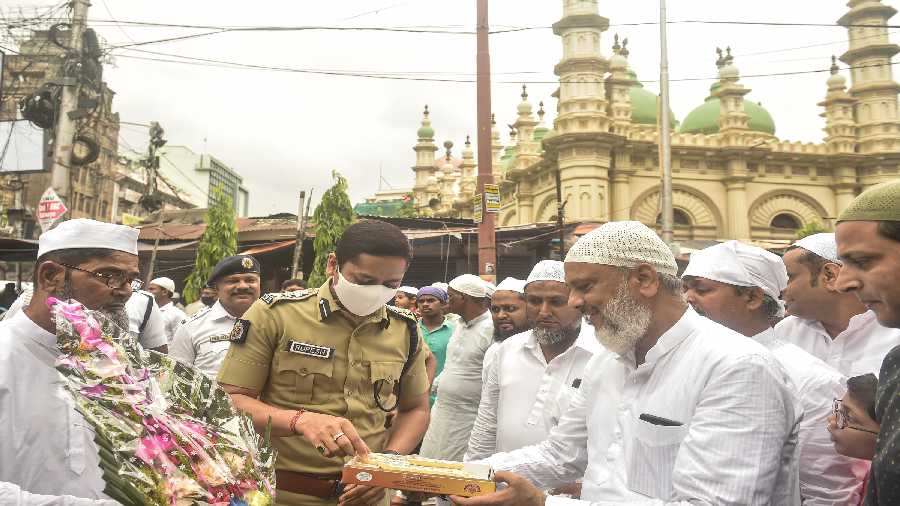Muslims offer sweets to police officials after offering prayer outside a mosque on the occasion of Eid-ul-Fitr