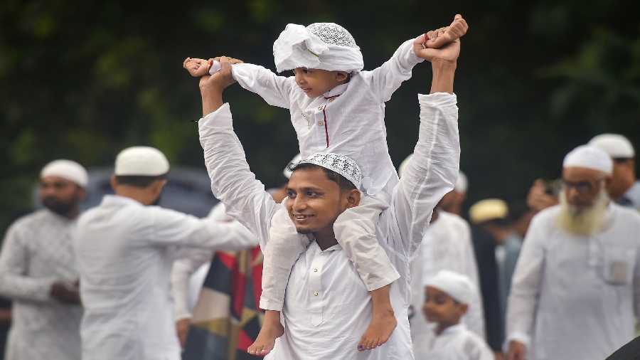 A Muslim man carries a child as they returns home after offering prayers at the Red Road