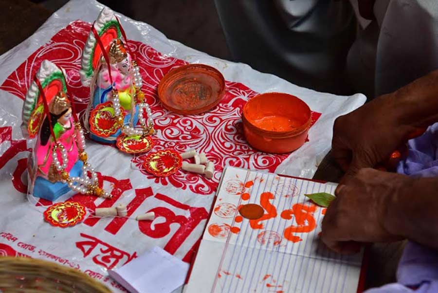 A Hindu priest draws religious symbols on a ledger book on Tuesday as part of the Akshaya Tritiya rituals