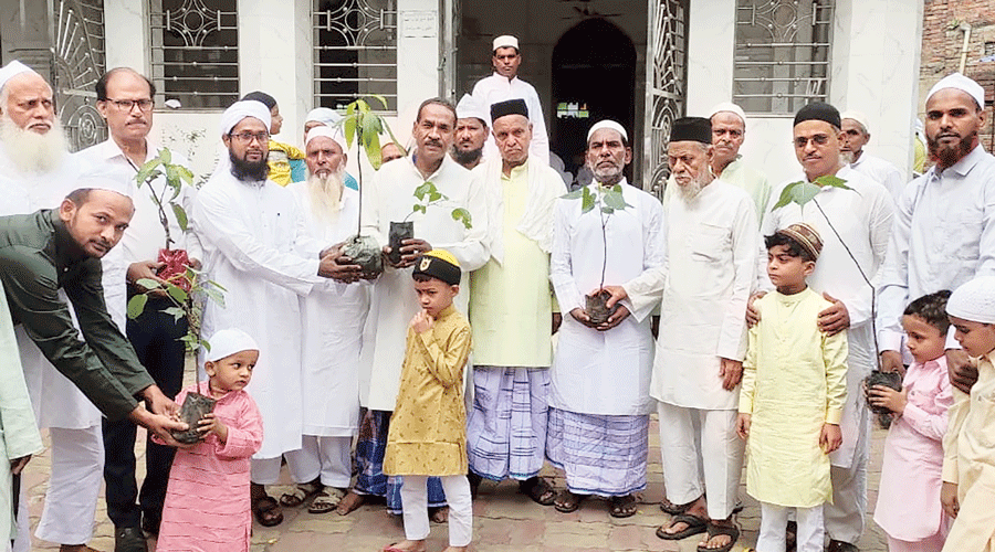 Akhlaq Ahmad (left in green kurta) gives sapling as Eidi on Madina Masjid on Id at Jharia, Dhanbad, on Tuesday.