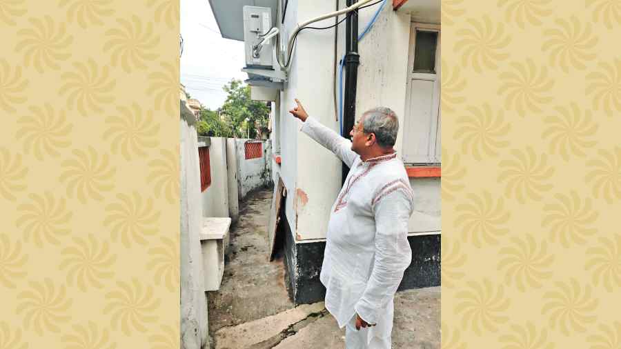 Kalyan Mitra points to the damaged pipes outside his BA Block home 