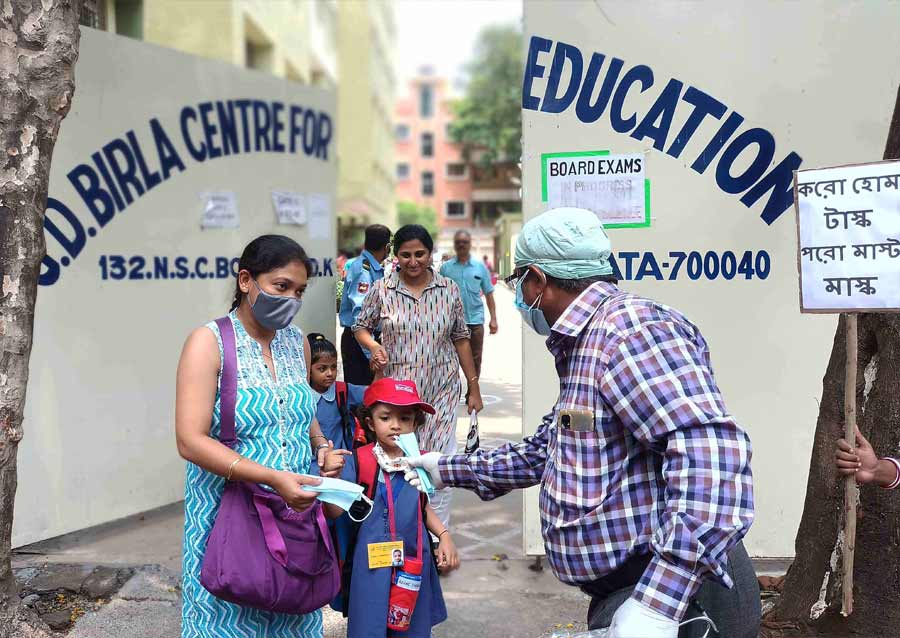 BETTER SAFE THAN SORRY: A man hands out masks to a child and her guardian at G.D. Birla Centre for Education on Wednesday, May 4, as part of an awareness campaign on the usefulness of mask against Covid-19