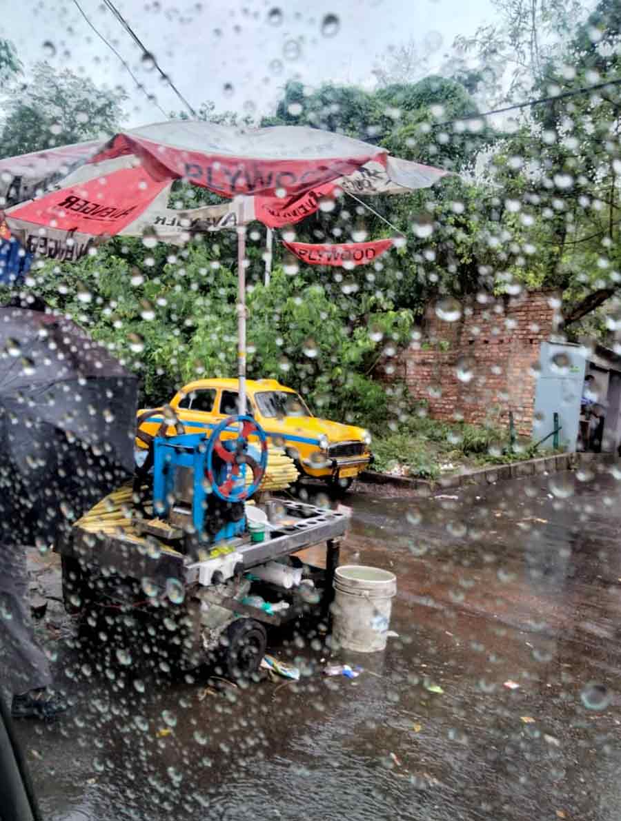 Apollo Hospitals, EM Bypass: An empty sugarcane juice-grinding machine and a yellow taxi both wait for customers in the rain. 