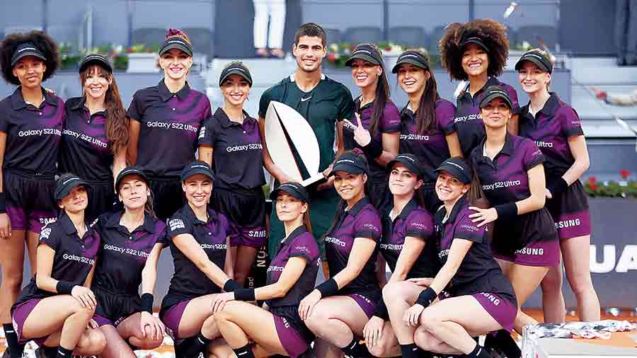 Carlos Alcaraz holds the Madrid Open winner’s trophy as he poses with the ballgirls in Madrid on Sunday