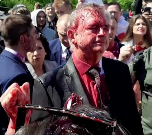Russia’s ambassador to Poland Sergey Andreev is covered in a red substance  by protesters in Warsaw  on Monday.