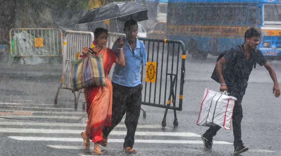People holding an umbrella cross a road amid heavy rainfall due to Cyclone Asani in Calcutta.