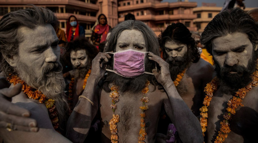 A ‘Naga Sadhu,’ or Hindu holy man, places a mask across his face before entering the Ganges river during the traditional Shahi Snan, or royal dip, at the Kumany patients suffocated. (Danish Siddiqui)