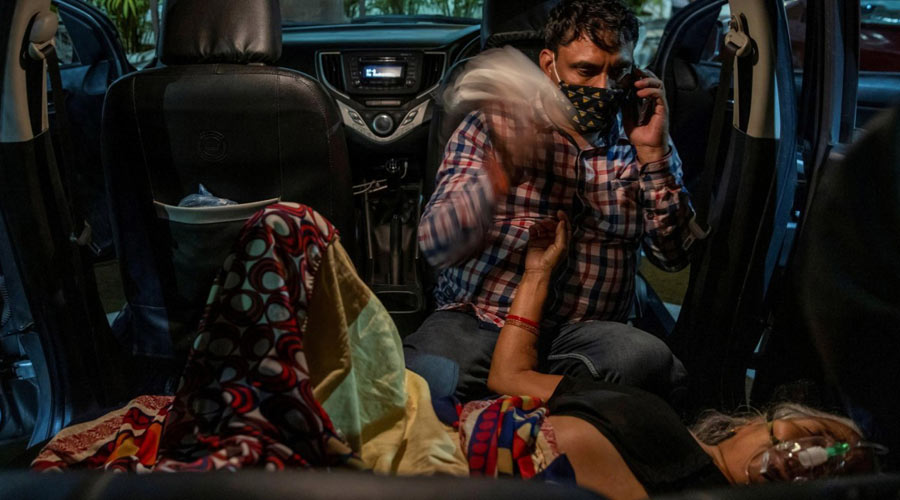 Manoj Kumar waves a handkerchief from the back seat of his vehicle at his mother Vidhya Devi as she receives oxygen in the parking lot of a Gurudwara (Sikh temple) amidst the spread of the coronavirus disease in Ghaziabad, India, April 24, 2021. (Danish Siddiqui)