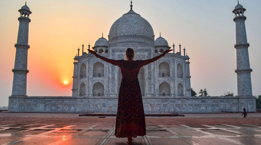  A tourist poses for photographs in front of the Taj Mahal during sunrise, in Agra on Thursday