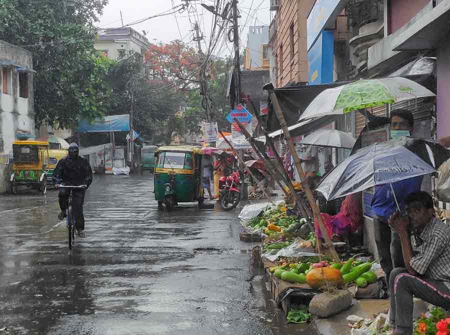 Vegetable vendors shield themselves from the rain with umbrellas on Thursday morning
