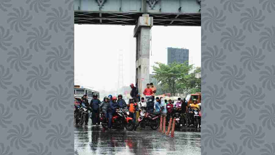 Commuters take shelter under a footbridge on EM Bypass, near Science City, during rain on Thursday morning.  