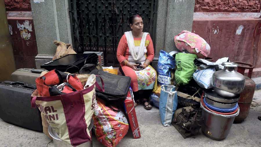 Resident waits with her belongings as she prepares to vacate her house after cracks appeared in the structures of the neighbourhood, likely to have been caused by metro railway construction in the area, at Bowbazar, in Calcutta
