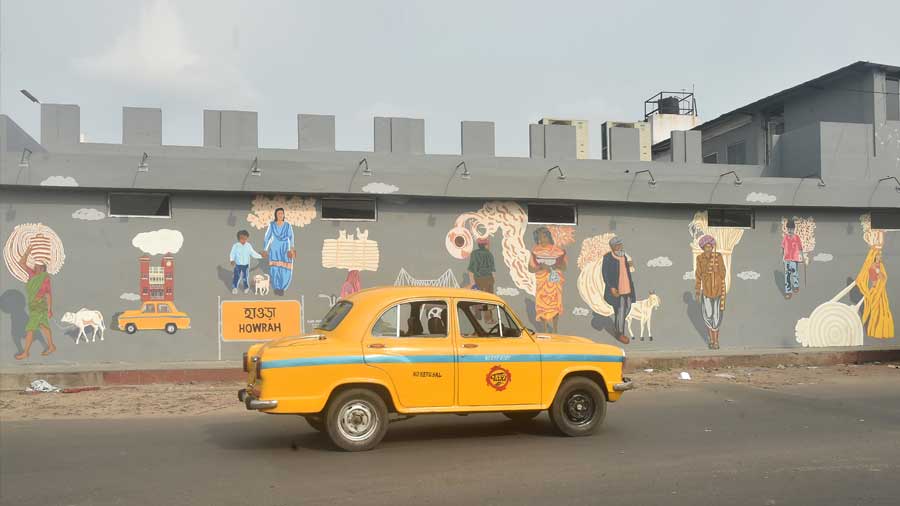 A yellow taxi drives past a mural dedicated to migrant workers near Howrah railway station on Friday