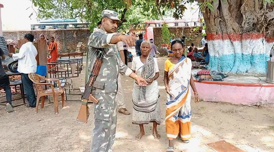 A security personnel guides voters at Dumaria block in East Singhbhum district on Saturday.