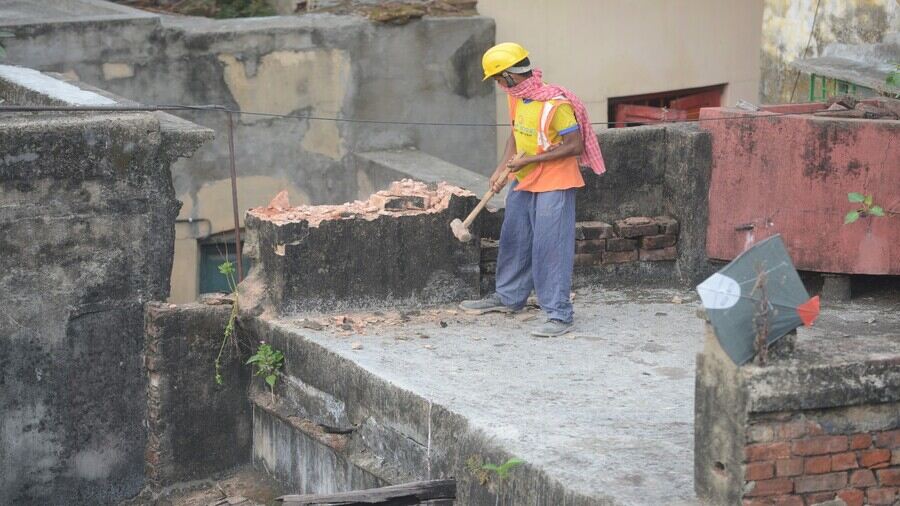 A worker uses a sledgehammer to demolish a wall in one of the subsidence-ridden houses in Bowbazar’s Durga Pituri Lane on Monday.
