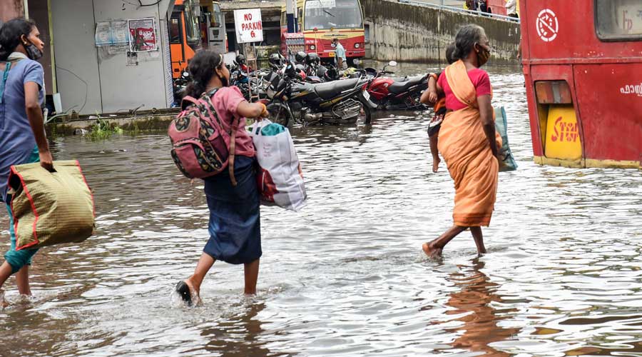 Commuters wade through a waterlogged road after heavy rain in Kochi