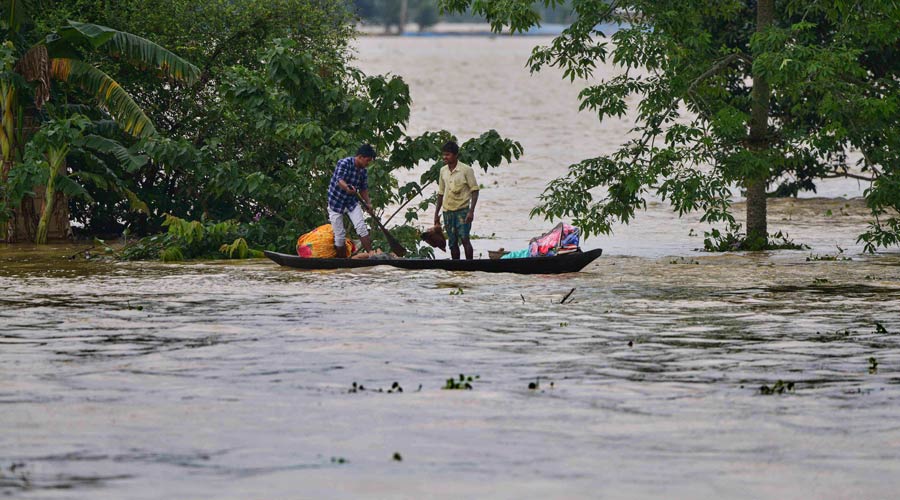 Villagers use a boat to move from a flooded area to safer places after rain at a village in Nagaon district