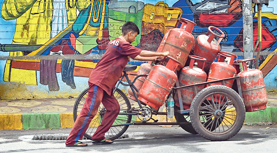 A worker transports LPG cylinders in  Mumbai on Thursday as the second price  increase this month comes into effect.