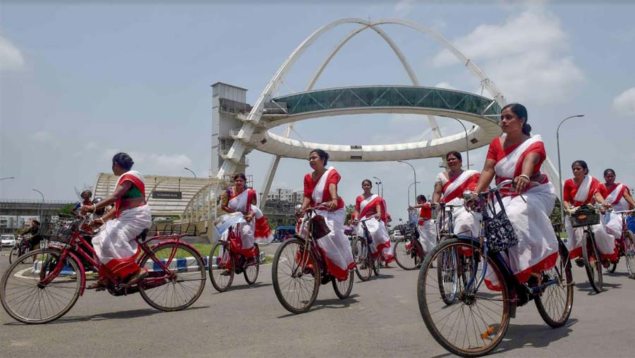 Several women clad in red and white saris ride past Biswa Bangla Gate on bicycles to celebrate Bike-to-Work Day on Friday