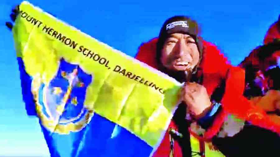 Pramod Shrestha ‘Goofy’ with the flag of Mount Hermon School atop Mount Everest.