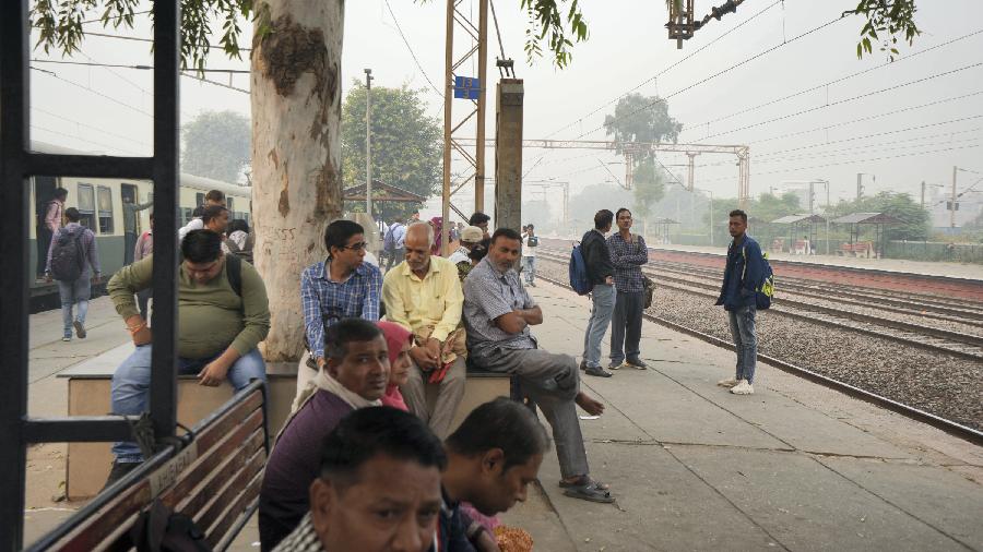 Commuters wait to board a train at a platform of Sahibabad Junction railway station amid heavy smog 