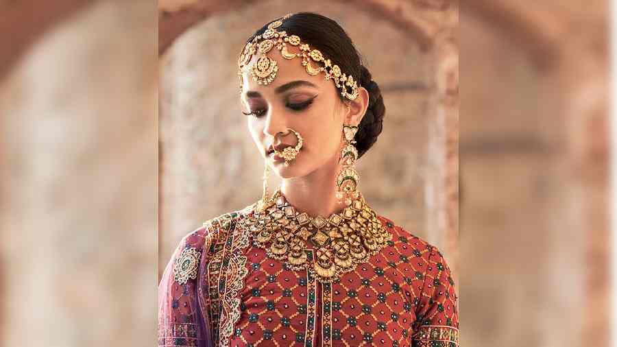A perfect look for the contemporary bride’s choice of statement pieces for her big day. The polki necklace and earrings are paired with polki and pearl mathapatti, polki nath, polki kada designed with emeralds and ruby and polki pacheli studded with emerald cabochon, set in 22k gold