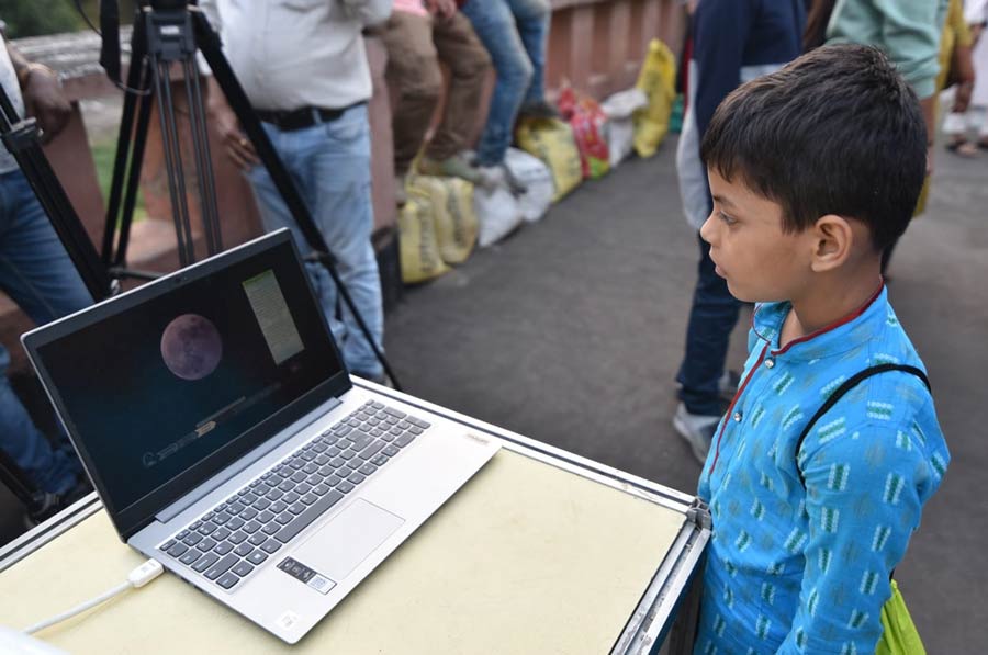 A young boy looks at a laptop screen showing the celestial event taking place