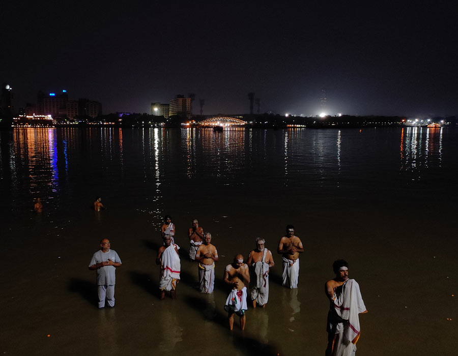 Devotees take a  bath during Lunar Eclipse at Howrah river side ghat on Tuesday