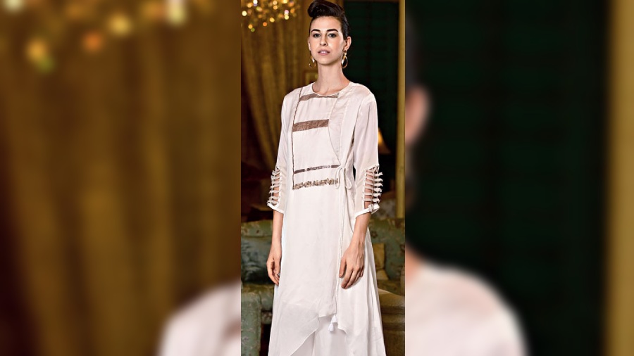 The traditional angrakha is styled with a modern twist in this silhouette to make it apt for a contemporary choice in fashion. The white crepe kurta is detailed with gold sequins to add a touch of glam