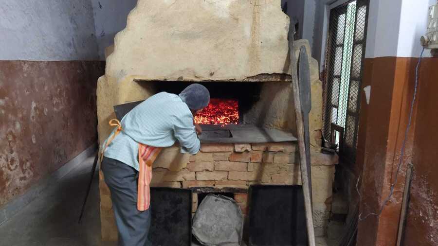 Amar Koley pre-heats the old, wood-fired oven while the girls pour out the batter into the cake tins 