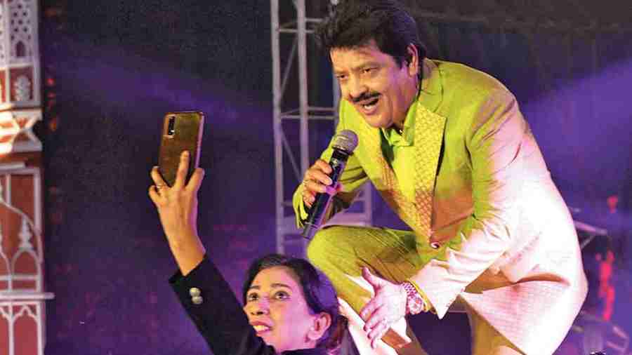 A fan clicks a selfie with the singer at the edge of the stage