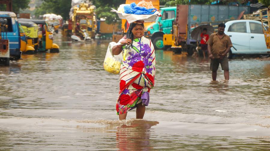A woman wades through a waterlogged road
