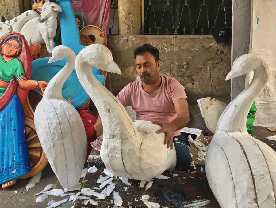 An artists prepares the framework of a peacock on the eve of Kartik Puja