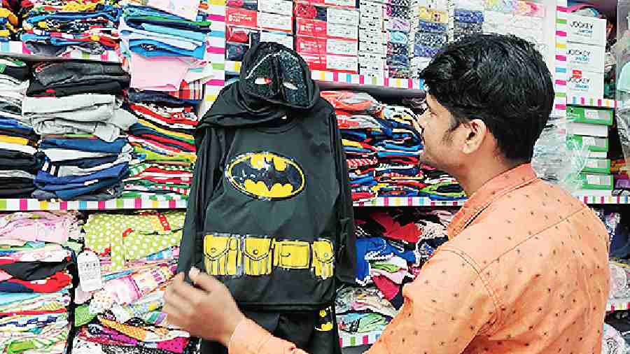 An employee at Lil Champs in City Centre puts up a Batsuit on display.