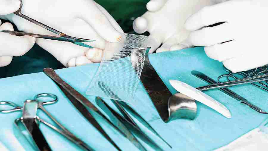 A surgeon prepares a mesh for a hernia surgery
