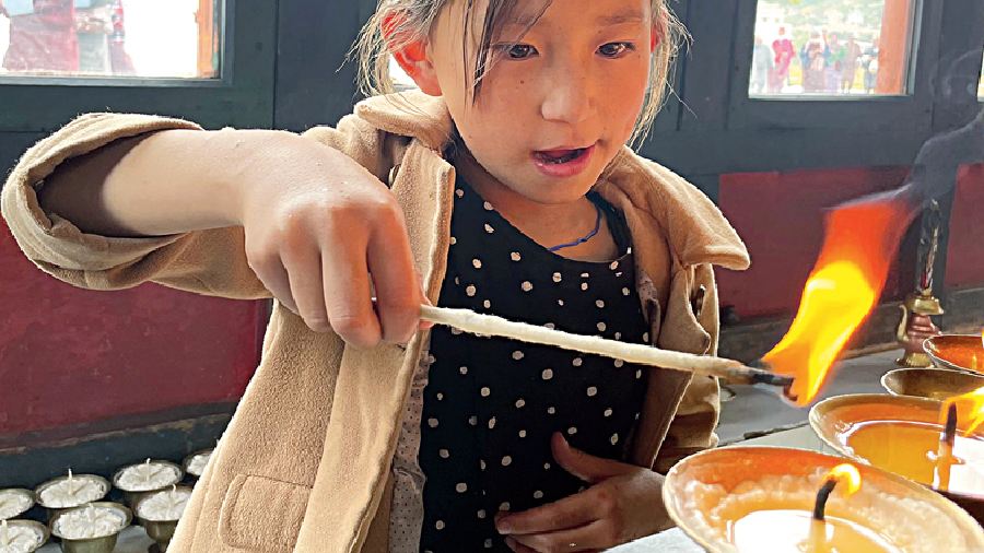 A girl lighting a butter lamp in a monastery