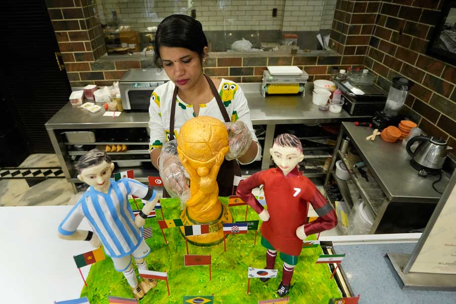 A confectionary shop employee in Kolkata readies a FIFA World Cup-themed cake featuring an edible replica of the championship trophy and figures of celebrated footballers Lionel Messi and Cristiano Ronaldo. Monday is the second day of the international football tournament being held in Qatar