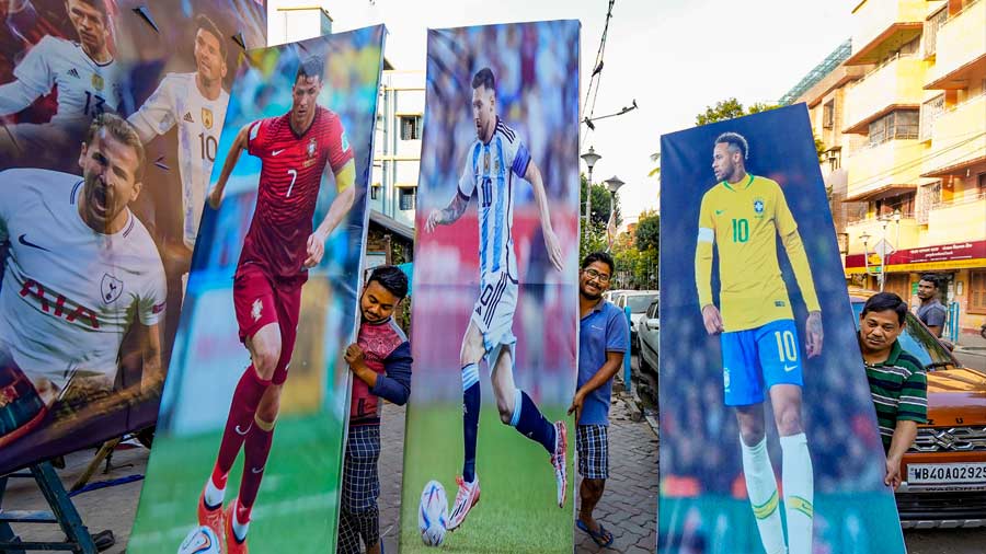 Workers carry hoardings of football players Cristiano Ronaldo, Lionel Messi and Neymar Jr. 