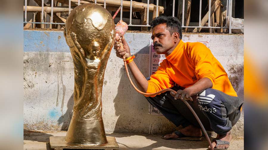 An artisan paints a clay model of World Cup trophy at his workshop.