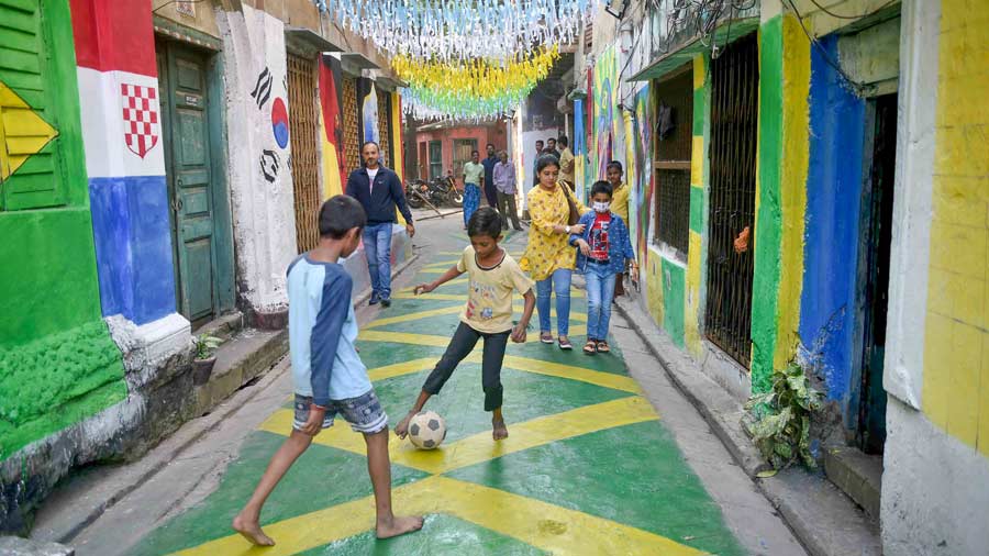 Children play football in a decorated neighborhood catches their football frenzy spirit. 