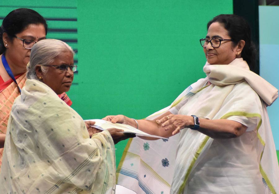 Chief minister Mamata Banerjee presents a beneficiary with land ‘patta’ (record of rights). The CM handed over the ‘pattas’ to several marginalised families from various districts of the state at the Netaji Indoor Stadium on Wednesday