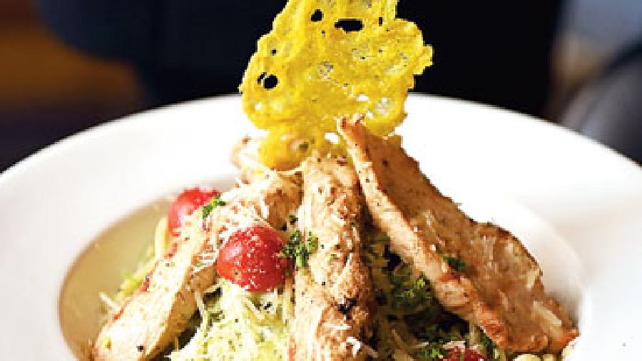 Double Impact: For some Italian love indulge in this delish recipe where spaghetti is cooked in fresh pesto sauce with pine nuts and then dusted with parmesan cheese for a creamy and nutty profile. It is served with grilled chicken and cherry tomatoes and topped with pasta parmesan biscotti