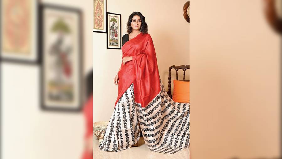A red-and-ivory sari is a classic combination to have in the wardrobe. Dyed in a dual tone of earthy red and ivory white, the sari is highlighted with a block-printed design. A perfect drape for a complete chunky silver jewellery look.